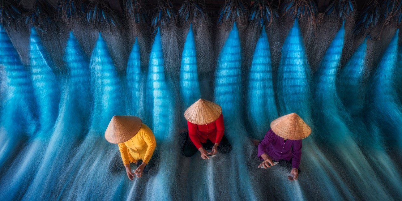 Pano view of workers in Vietnam repairing fishing nets
