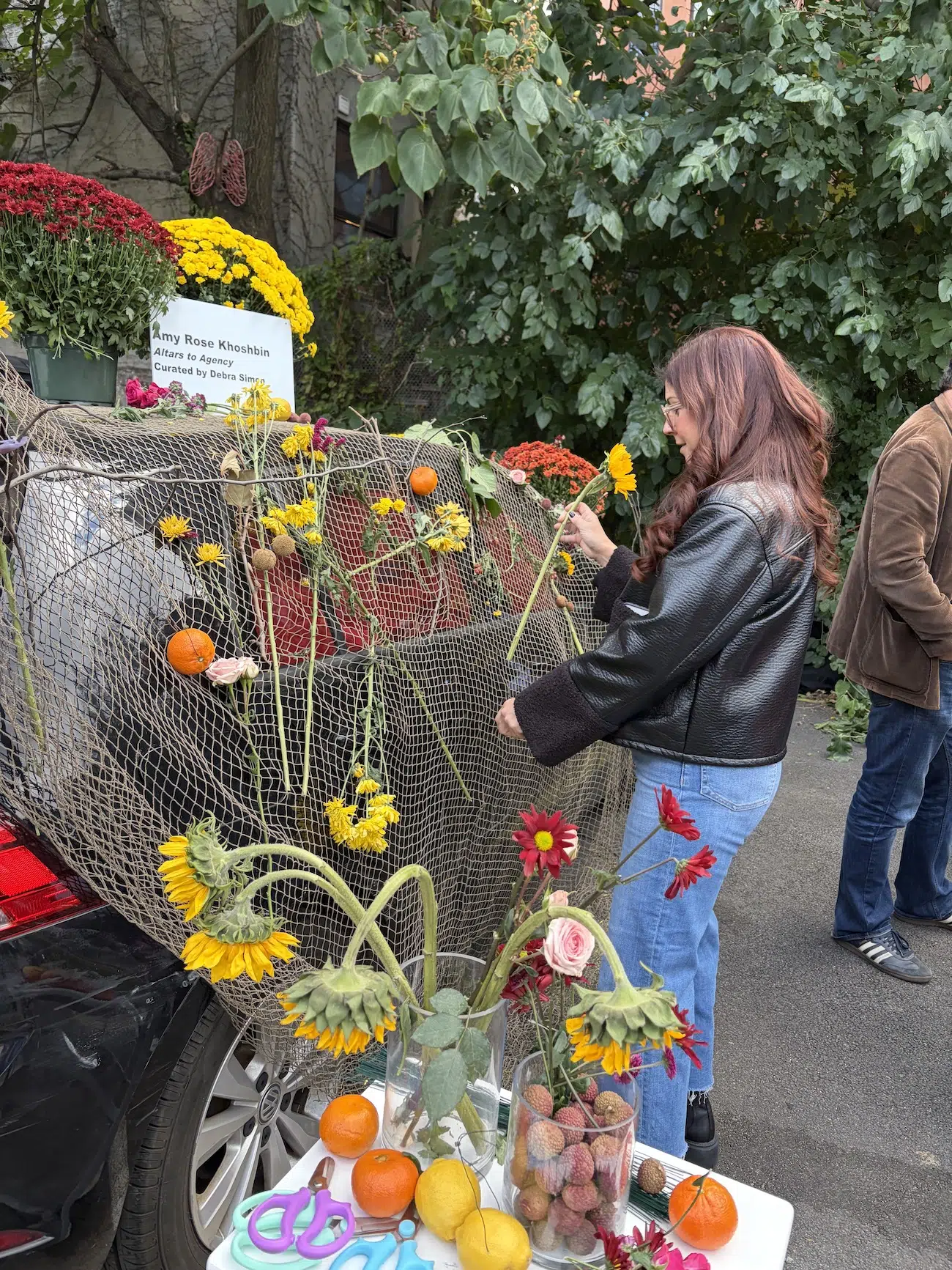 Amy Khoshbin, "Atlars to Agency." A participant adds flowers to the installation.