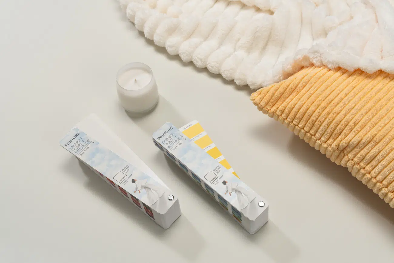 Cloud Dancer swatches beside a pillow, blanket, and candle