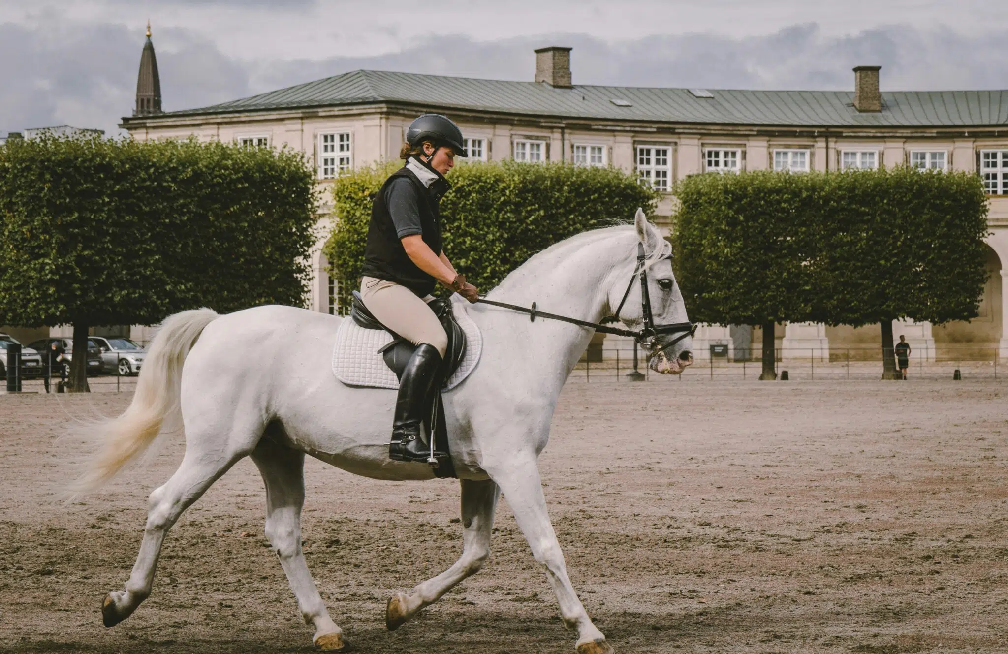 A white horse being ridden by a girl in a courtyard
