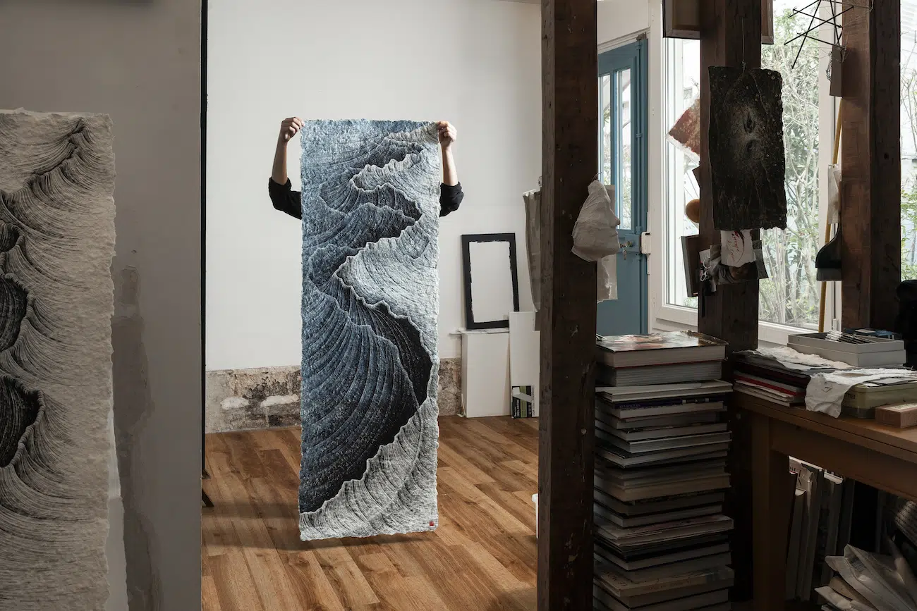 Lee Hyun-Joung holding up one of her artworks