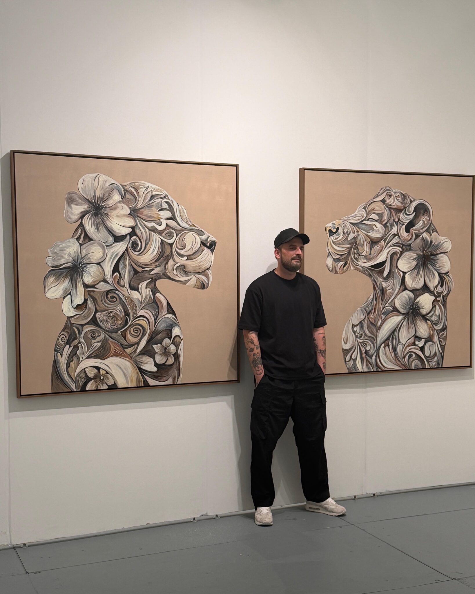 Marcel van Luit standing in front of two of his artworks, both of which resemble lions