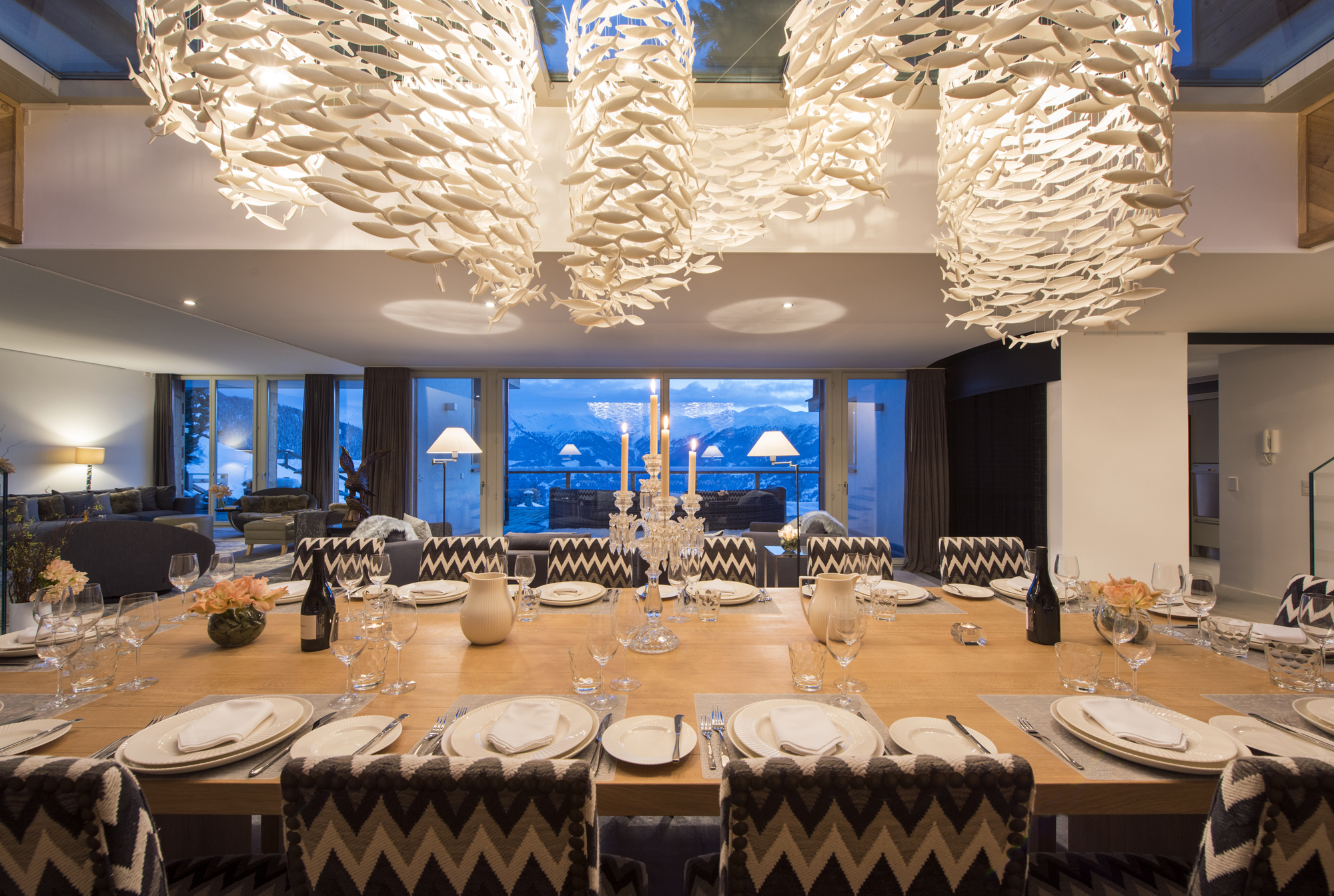 A flowing Scabetti chandelier composed of white ceramic fish hanging above a dining table