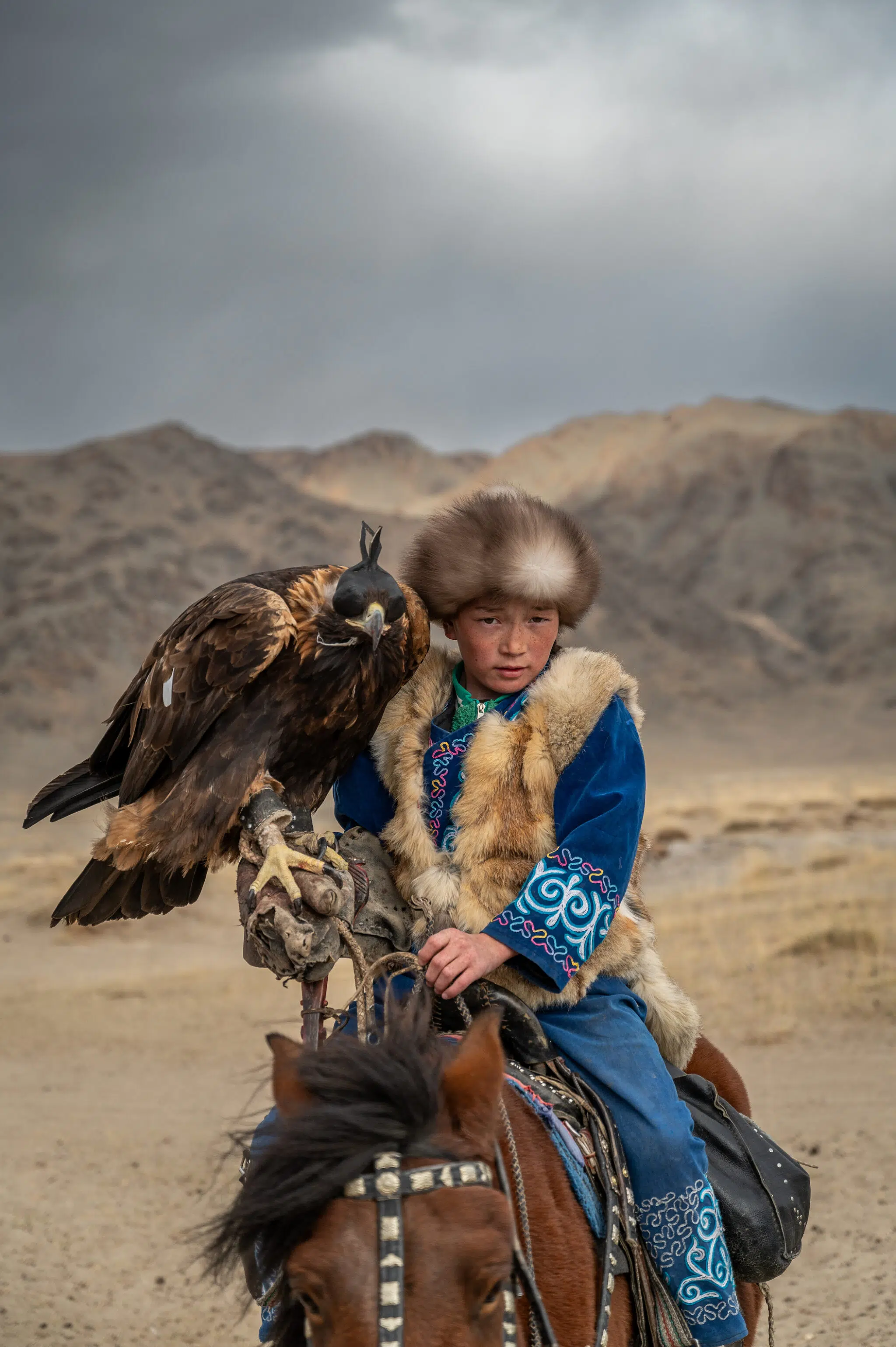 Aykerim, 12, rides her horse while carrying a golden eagle on her arm