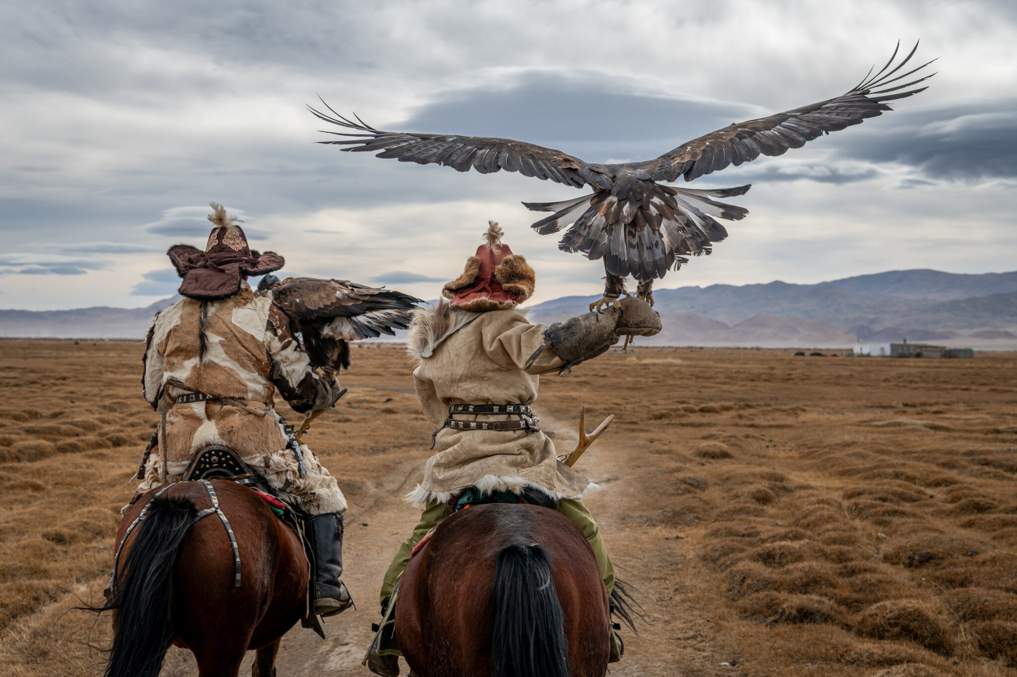 Father and son, Alakosh (l.) and twelve-year-old Arkalak, ride with their golden eagles near their family home in the Altai Mountains.