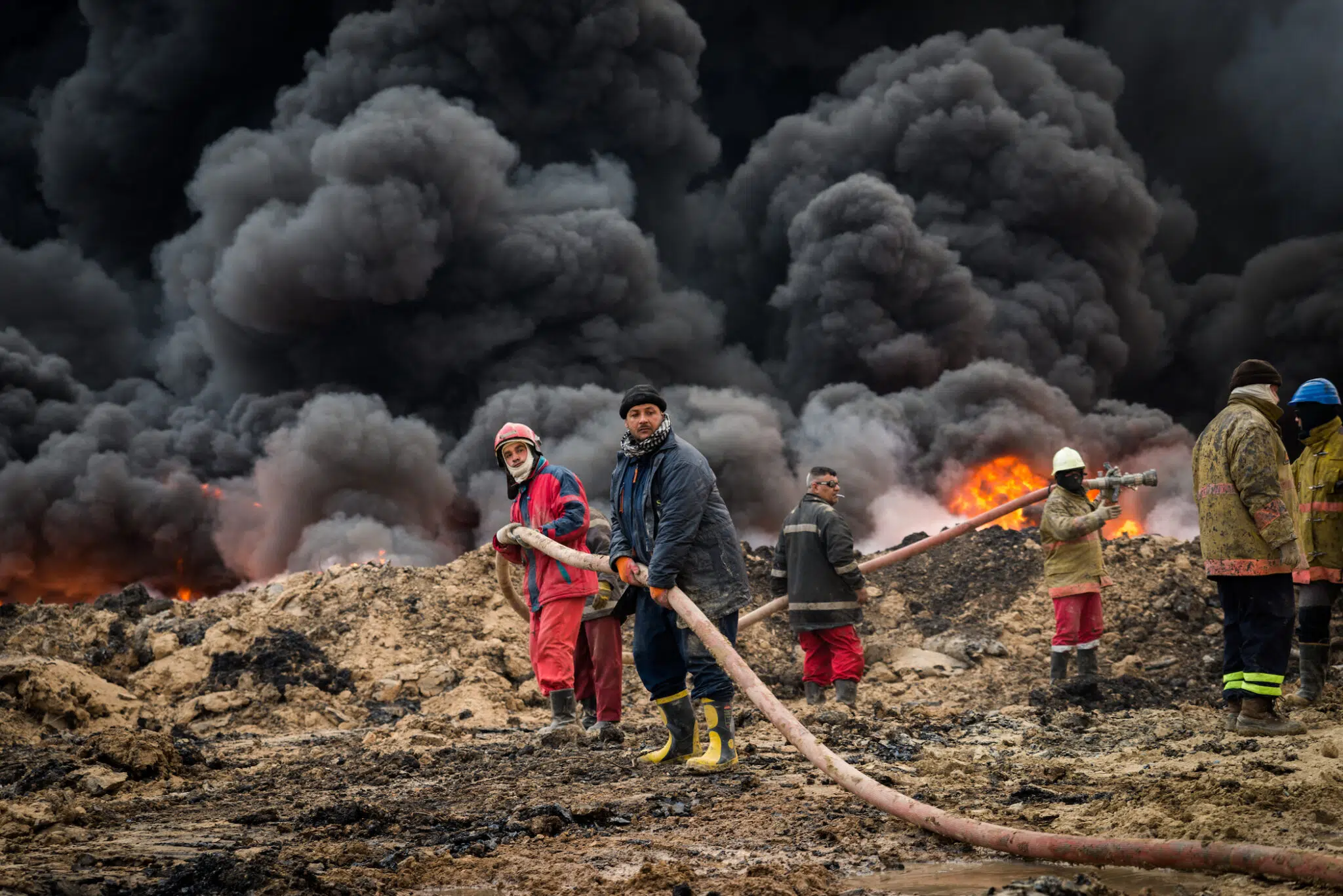 Firefighters drag a hose toward a fire. There are around 150 men working on this fire, including 28 firefighters, machine operators, engineers and mechanics.