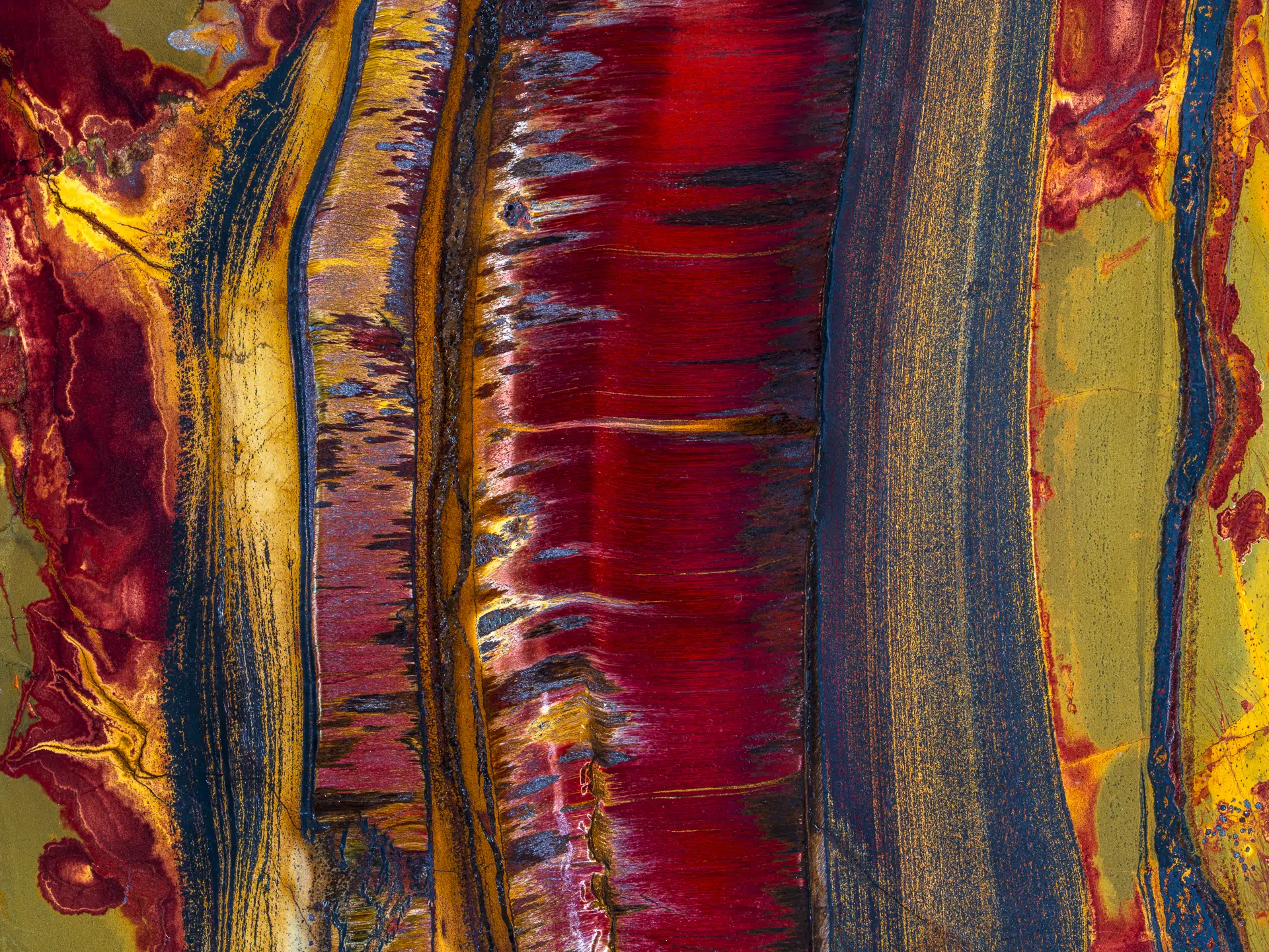 Australia, 2025. Tigerite from Australia&rsquo;s Northern Territory is formed when silica-rich fluids replaced ironstone within ancient sediments, preserving bands of fibrous quartz intertwined with iron oxides such as hematite and goethite. Golds and yellows emerge where iron oxidized slowly; deep reds and browns mark areas of higher iron concentration; and blues and greys appear where silica dominates.