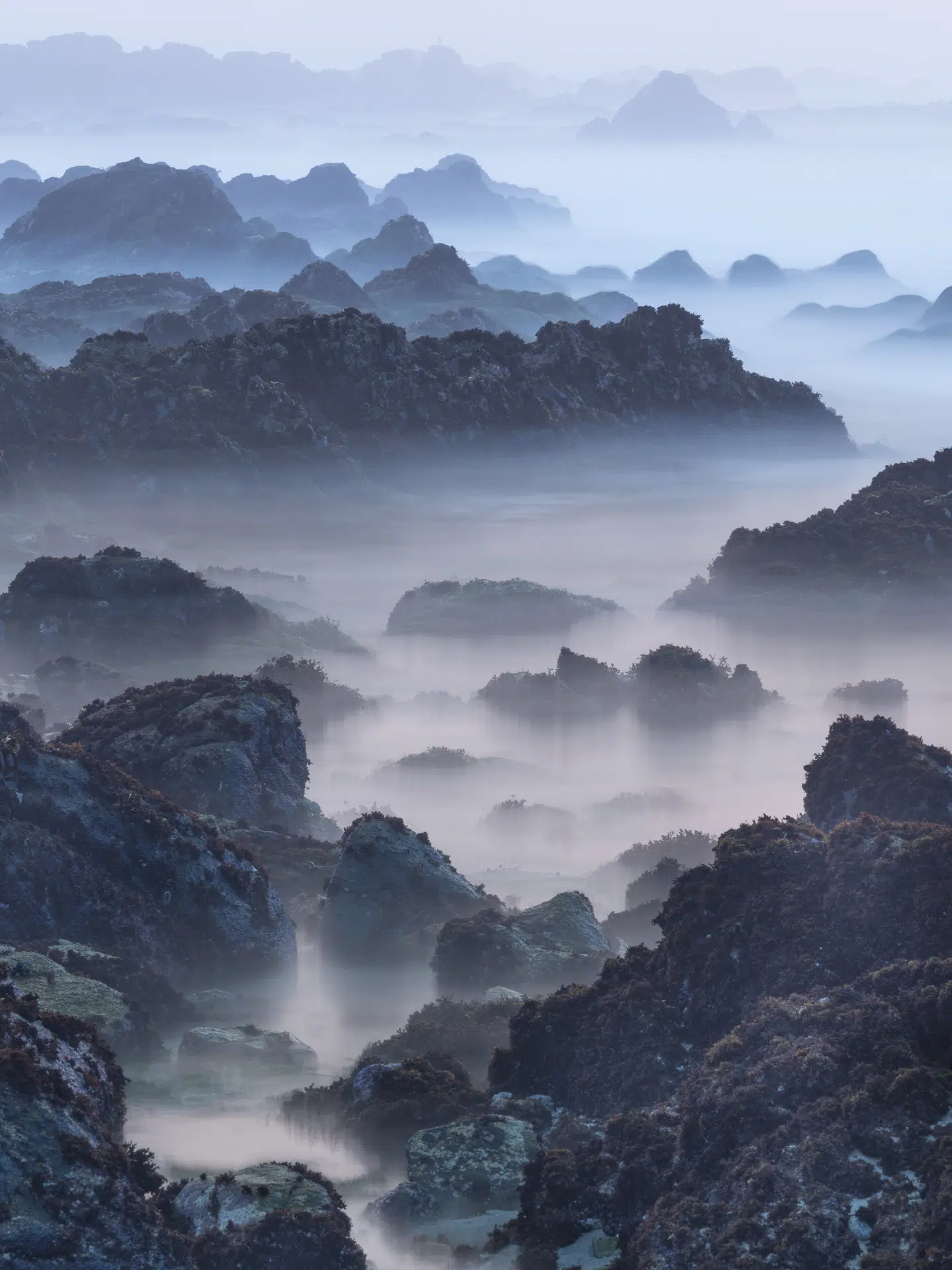 California, 2020. In the blue hush of twilight, the beach rocks of Northern California begin to resemble China&rsquo;s karst mountains because light, scale, and erosion briefly align.