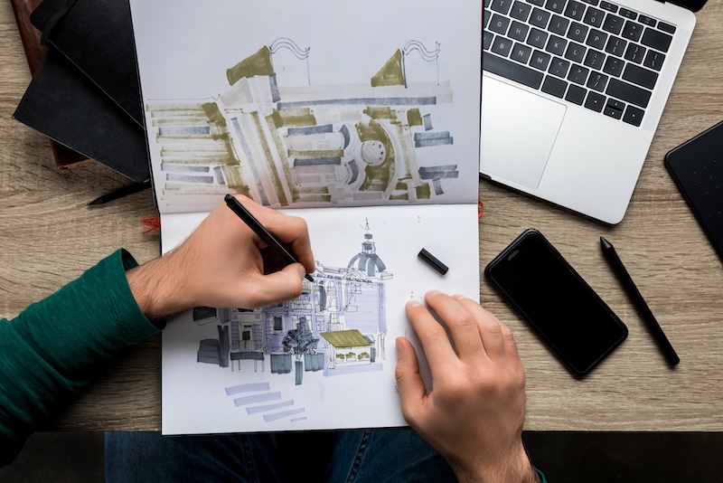 Overhead shot of hands drawing architecture in a sketchbook