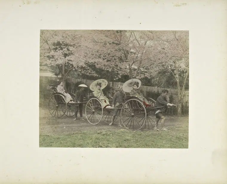 Hand-colored photograph of women riding in richshaws in 19th-century Japan