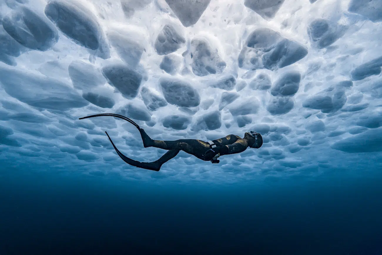 &copy; James Ferrara (USA). Connecting Oceans &mdash; 3rd Place. A freediver glides beneath the frozen surface of North America&rsquo;s Lake Huron, suspended in a silent and surreal world. The view from below reveals intricate patterns in the ice, sculpted by weather and waves. Experiencing a scene like this makes braving the elements more than worthwhile.
