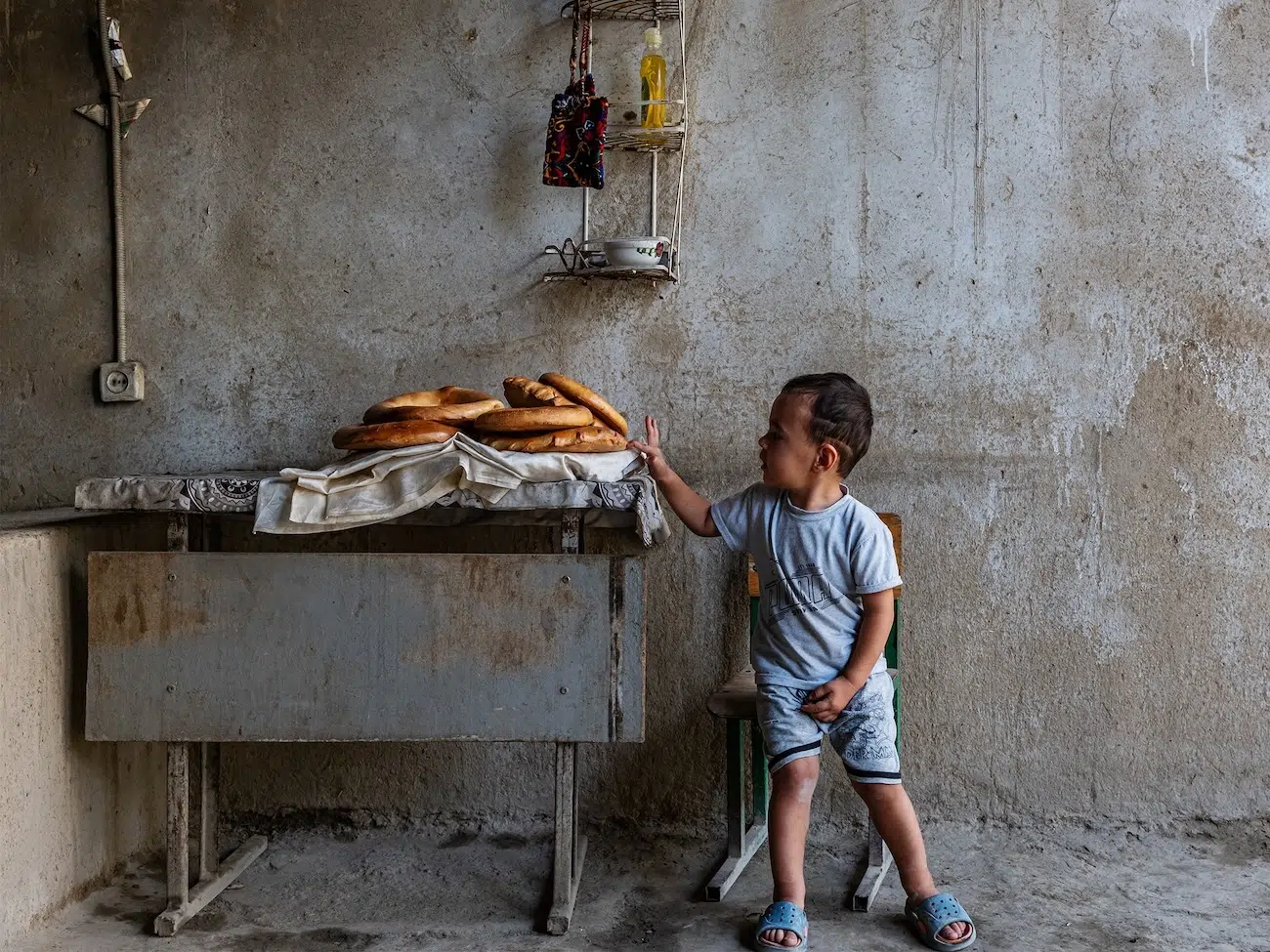 Kid about to touch a plate of bread