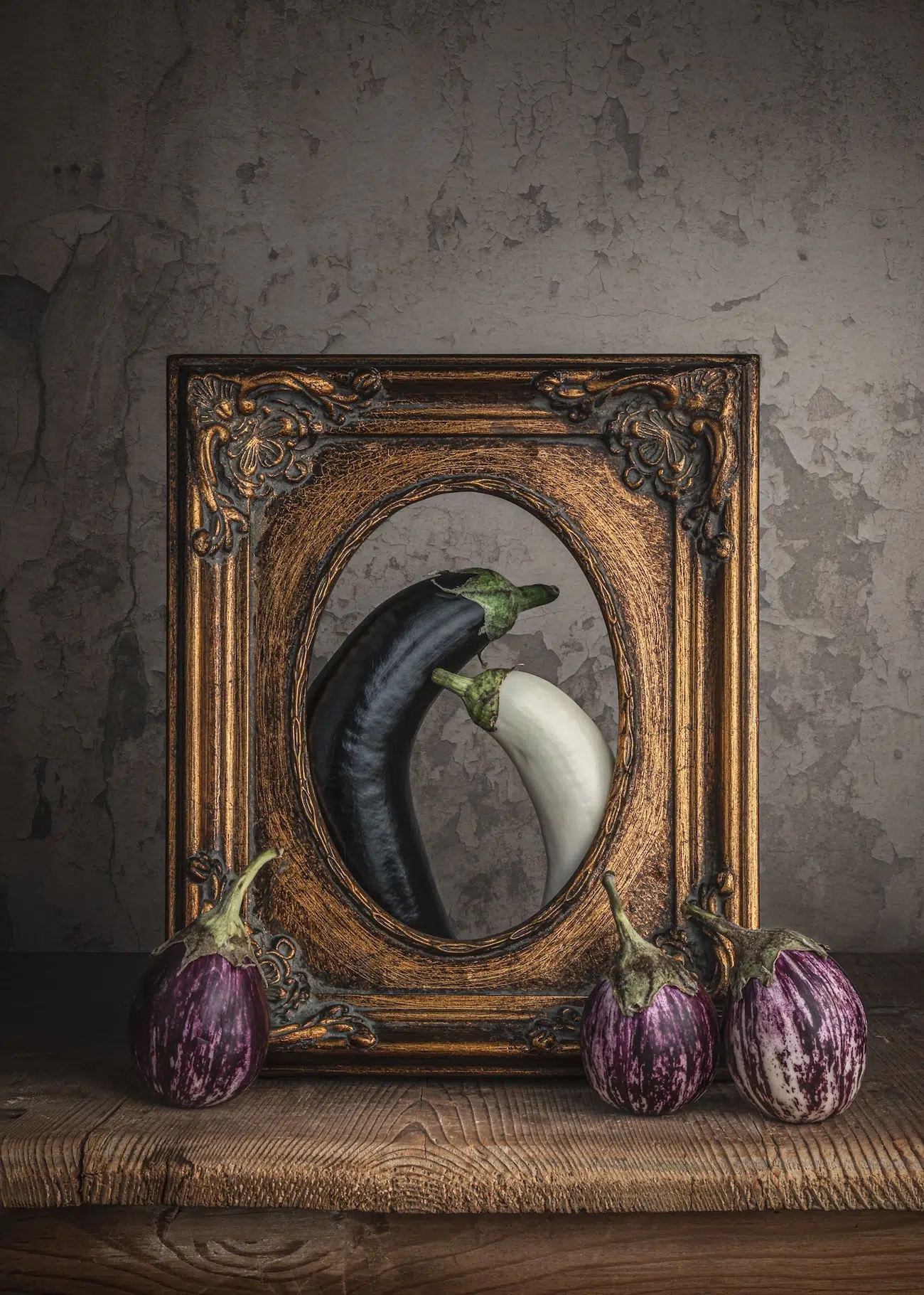 Eggplants arranged behind an ornate gilded antique frame