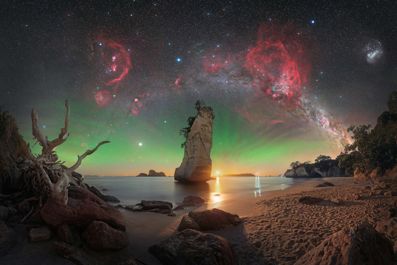 Skyscapes. "Te Hoho Rock Moonrise" © Evan McKay (Aotearoa/New Zealand). On this particular night, Evan McKay had only a small window to capture the sky before the Moon started to rise. McKay polar-aligned his mount during twilight and then began shooting the sky panorama from this location. The moonlight provided the best of both worlds and did a fantastic job of lighting up the foreground. To enhance the sky, McKay captured a separate panorama using a dual narrowband filter and blended it in to bring out the nebulae. Taken with a Nikon Z 6a camera, Sky-Watcher EQ6-R Pro mount, Move Shoot Move Nomad star tracker, Sigma 40 mm Art lens, Optolong L-Para filter, 40 mm, Foreground: f/2.8, ISO 800, 30-second exposure; Sky: f/2, ISO 1600, multiple 15-second RGB exposures, multiple 2-minute exposures with filter Location: Cathedral Cove, Waikato, North Island, Aotearoa New Zealand, 8 January 2026