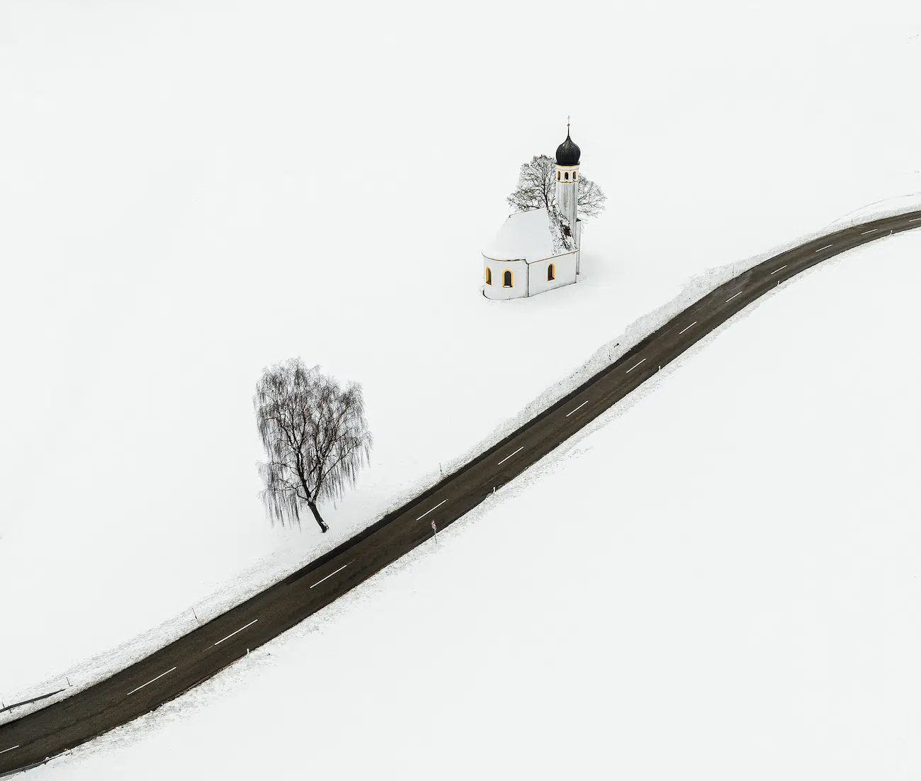 Aleksandra Wilk, Germany. Water in Bavarian Countryside. Winter in the Bavarian countryside near Lake Ammer. The onion-domed roof is characteristic of southern Germany. My intention was to capture this church which stood on a street, with nothing to disturb the composition, all white in a graphic style.