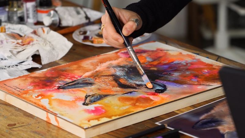 Artist Dimitra Milan Working on an Painting of a Fox on an Abstract Background