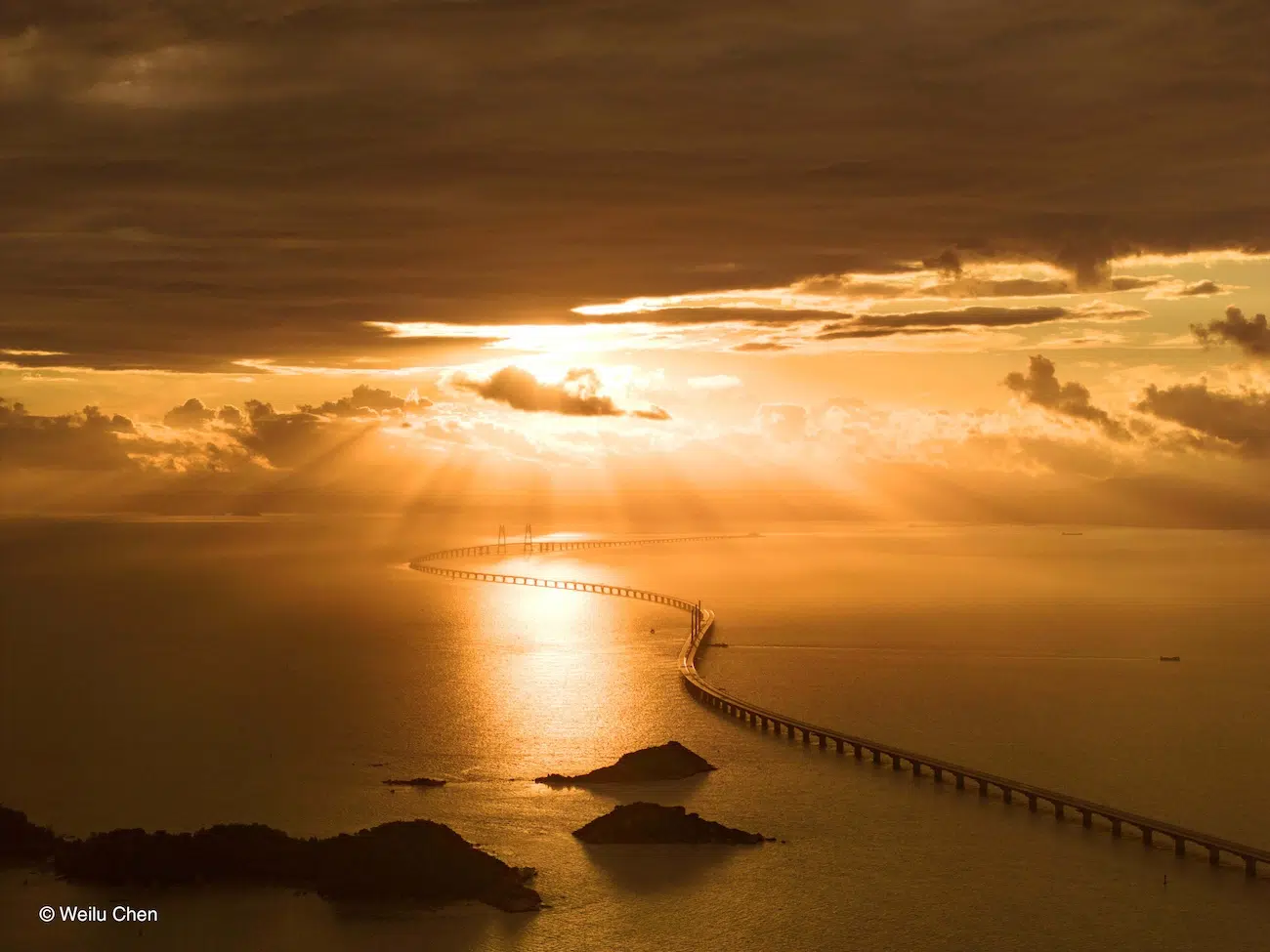 Photo of sun breaking through clouds over the ocean.