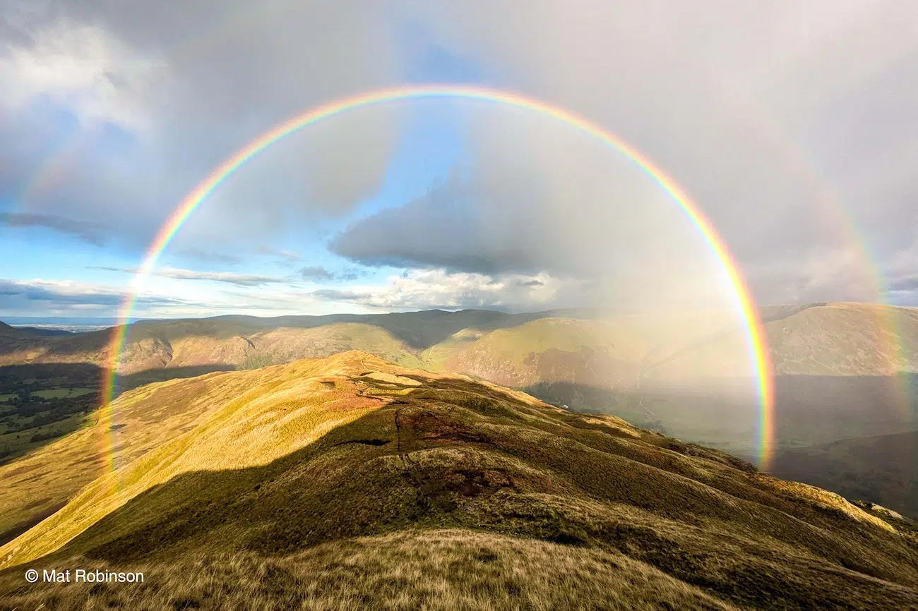 Photo of rainbow over mountains.